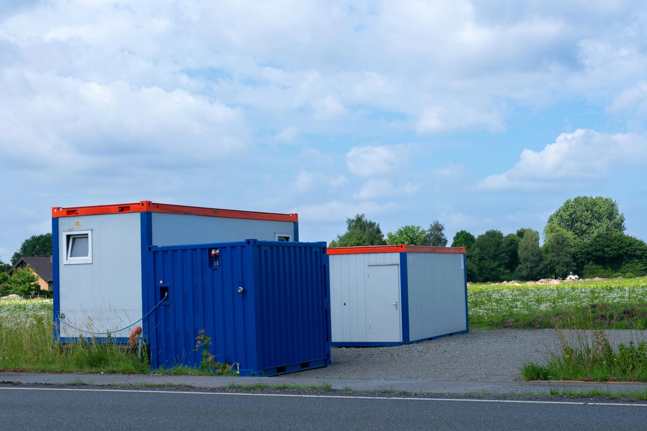 Container-style battery energy storage enclosure in a green setting with trees
